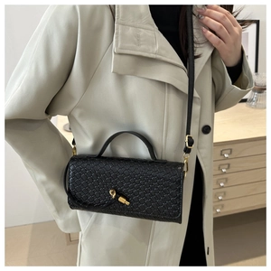 Détail d'un sac à bandoulière en cuir tressé avec boucle en nœud doré et sangle réglable