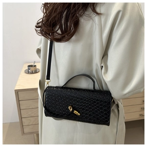 Détail du sac à main en cuir tressé noir avec boucle dorée dans un cadre de vie élégant