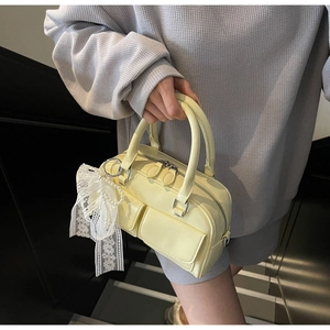 Detail of yellow Boston handbag with lace pearl charm and front flap pockets