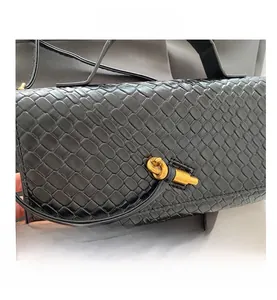 Détail du sac en cuir tressé noir avec un fermoir métallique doré en forme de nœud
