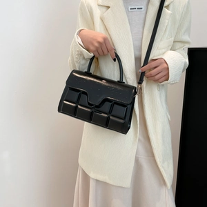 Schicke schwarze Handtasche mit 3D-Karomuster kombiniert mit einem modernen beigen Blazer