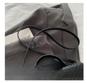 Détail de la bandoulière en cuir noir tressé avec boucle dorée du sac à main