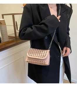 Gros plan d'un sac bandoulière rose avec clous argentés et chaîne sur un mannequin