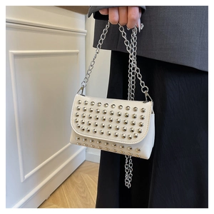 Détails d'un sac blanc en similicuir avec rivets argentés et chaîne de style punk rock