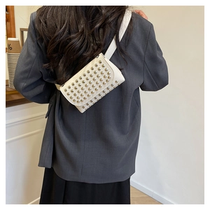 Détail du sac de taille en cuir blanc avec rivets métalliques et fine bandoulière