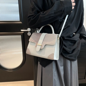 Minimalist light blue handbag with crocodile texture, featuring top handle and gold clasp