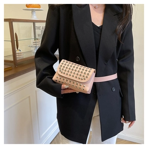 Détail du sac banane rose clair avec clous argentés sur un blazer noir style punk