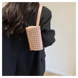 Petit sac à bandoulière rose style punk avec rivets dorés porté sur un blazer