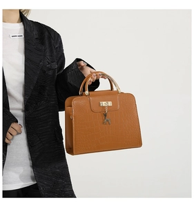 Detail of brown crocodile pattern leather handbag featuring a golden deer pendant