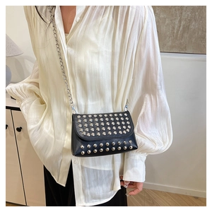 Détail du sac bandoulière noir avec rivets argentés et bandoulière en chaîne