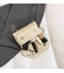 Détail du sac à rivets crème montrant l'espace intérieur pour téléphone et maquillage