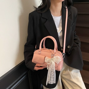 Pink bowling handbag with white lace bow and pearl charm shown on model in stairway