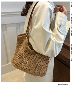 Detail of hollow crochet woven shoulder bag with dark brown leather straps and metal rivets
