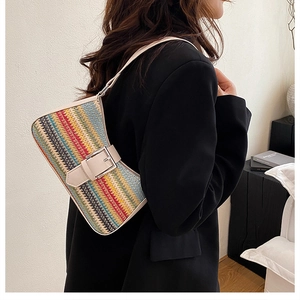 Close-up of a colorful rainbow woven shoulder bag featuring a white leather strap and silver buckle