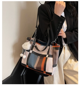 Detail of checkered tote bag featuring leather metal chain handles and cloud charm accessory
