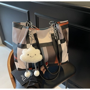 Macro detail of plaid tote bag with colorful patchwork design and plush cloud charm