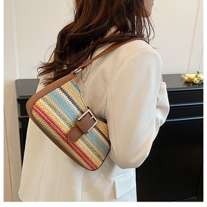 Detail of colorful woven straw bag with brown leather trim worn by model in white suit