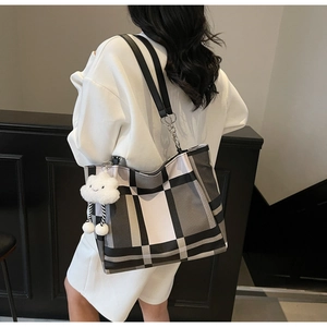 Side view of large black and white checkered tote bag with plush cloud charm and leather strap