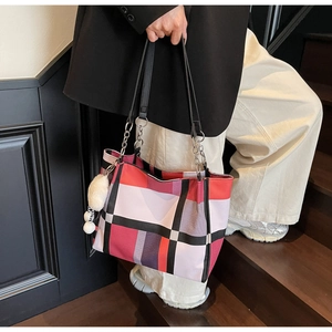 Detail of checkered tote bag with plush charm and silver chain strap attachment