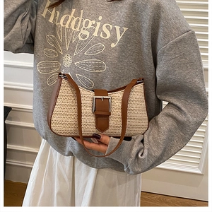 Detail of woven straw handbag featuring two-tone beige and brown leather flap with buckle