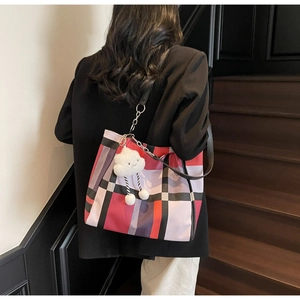Detail of checkered tote bag with plush cloud charm on a shoulder strap shown on model