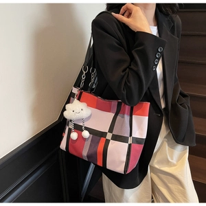 Detail of colorful plaid tote bag with metallic chain strap and plush cloud charm