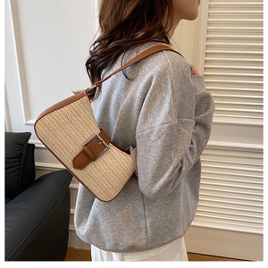 Détails d'un sac à bandoulière en paille tissée avec garniture en cuir brun et boucle