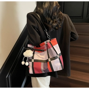 Detail of colorful geometric plaid tote bag with plush cloud charm on leather strap