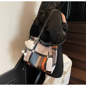 Close-up of color-block plaid tote bag with metal chain and cloud charm detail