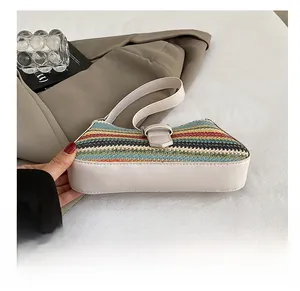 Detailed view of multi-color woven straw bag with white leather trim and buckle