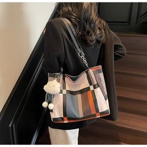 Detail of checkered tote bag with orange and blue patches and white cloud charm