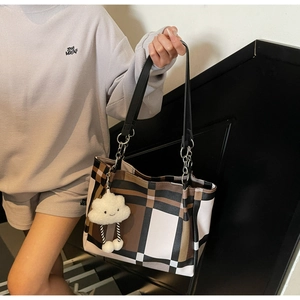 Detail of a large checkered tote bag with plush cloud keychain shown on shoulder