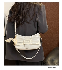 Détail du sac plissé blanc avec boucle décorative et petit foulard en soie floral attaché