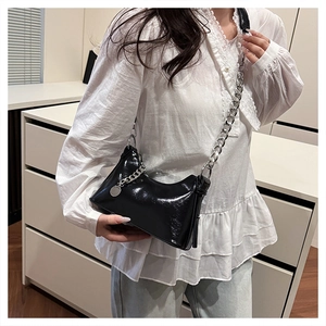 Détail du sac à bandoulière en cuir verni noir brillant avec chaîne argentée sur mannequin