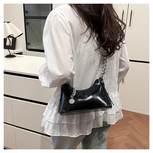 Détail du sac à bandoulière en cuir verni noir brillant avec grosse chaîne argentée