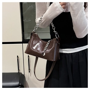 Détail du sac bandoulière en cuir brillant avec poignée en chaîne argentée