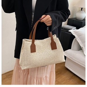 Detail of herringbone woven straw bag with premium brown leather straps and texture