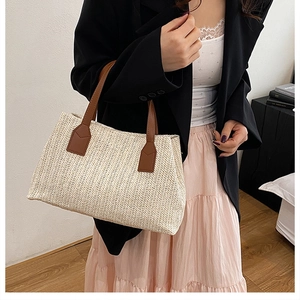 Detail of hand-woven straw tote bag with V-shaped texture and brown leather handles