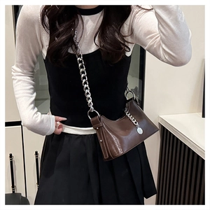 Sac bandoulière trapèze en cuir marron avec chaîne argentée porté par un mannequin
