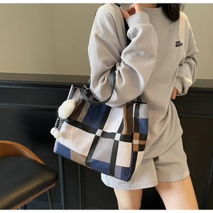 Detailed view of large tote bag with geometric color-block design and white pompom charm