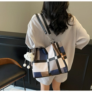 Detail of color-block tote bag featuring geometric patterns and fluffy cloud pendant