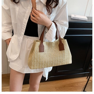 French retro style large straw tote bag with brown leather handles held by a model