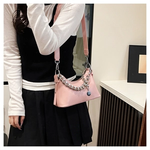 Détail du sac bandoulière rose clair avec chaîne argentée et pendentif métallique
