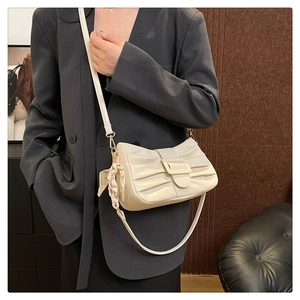 Détail du sac à bandoulière plissé crème avec foulard en soie sur un mannequin chic