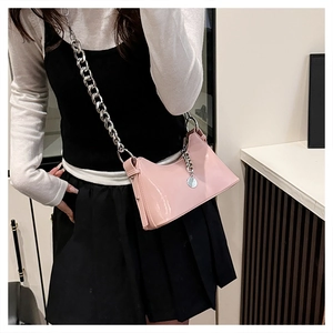 Détail du sac à bandoulière rose en similicuir avec chaîne argentée et pendentif en métal