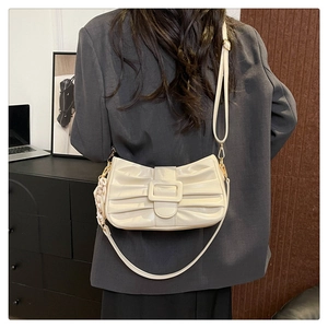 Gros plan d'un sac plissé beige avec boucle sur un mannequin portant un costume gris