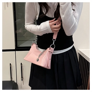 Détail du sac à main en cuir verni rose avec chaîne argentée et clous métalliques sur les côtés