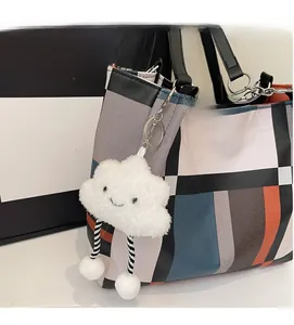 Detail of geometric color block tote bag featuring a cute white cloud plush pendant charm