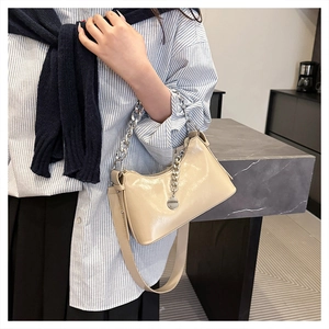 Gros plan sur le sac porté épaule beige avec chaîne argentée et texture cuir brillant