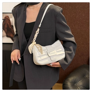 Détail du sac sous l'aisselle en cuir verni plissé blanc avec foulard et boucle décorative